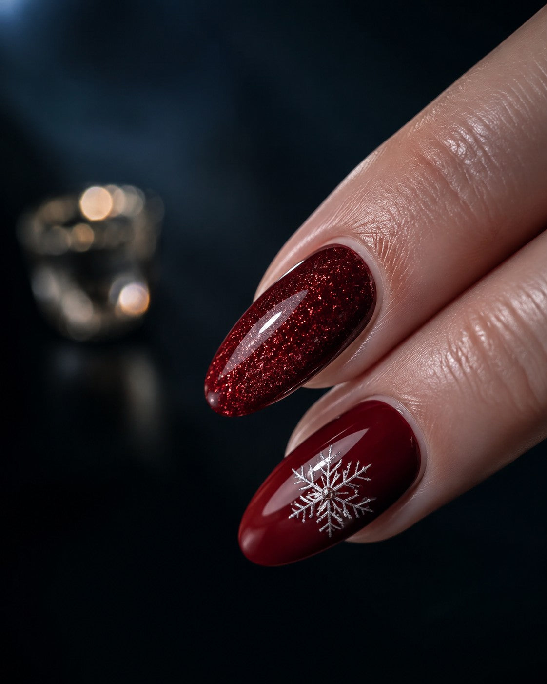 Cranberry red Christmas press-on nails with gold glitter and a white snowflake accent