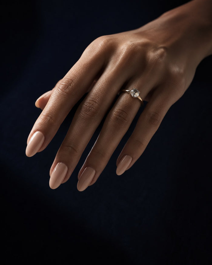 A finished hand wearing a complete set of nude almond press-on nails