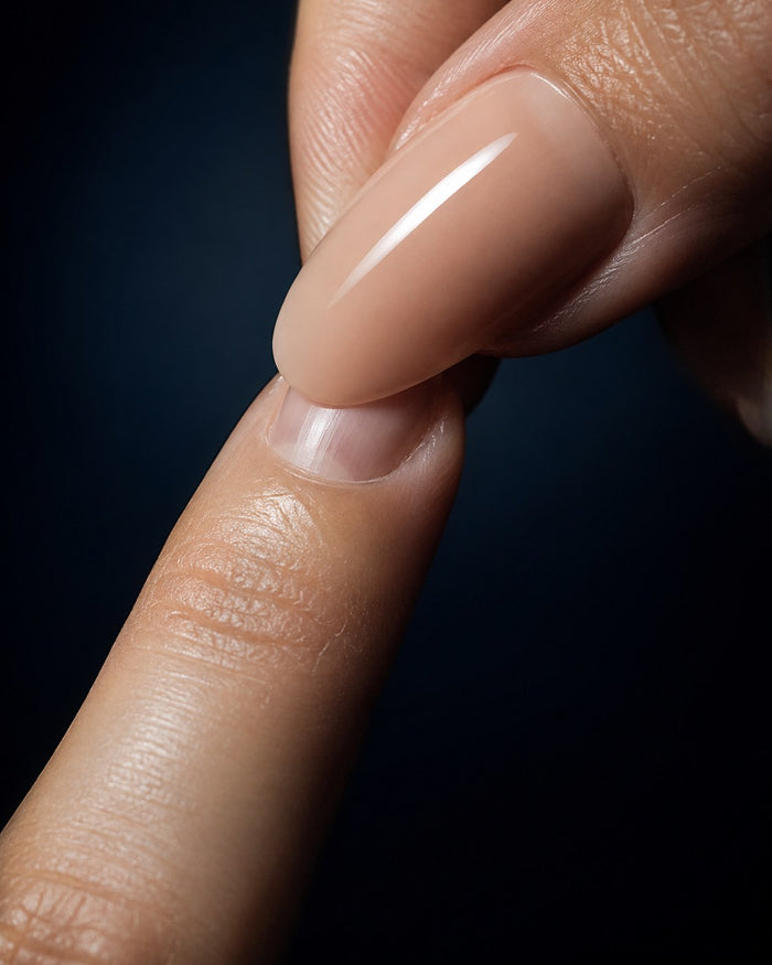 Pressing a nude press-on nail onto the natural nail at the cuticle line