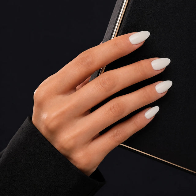 Milk Glaze Press-On Nails, Medium Almond — Main sur pochette noire (liseré doré)