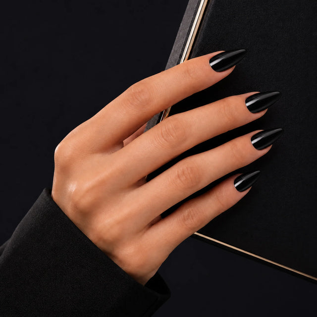 Noir Press-On Nails, Medium Almond — Main sur pochette noire (liseré doré)