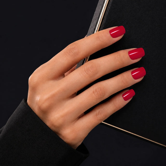 Rouge Press-On Nails, Short Square — Main sur pochette noire (liseré doré)
